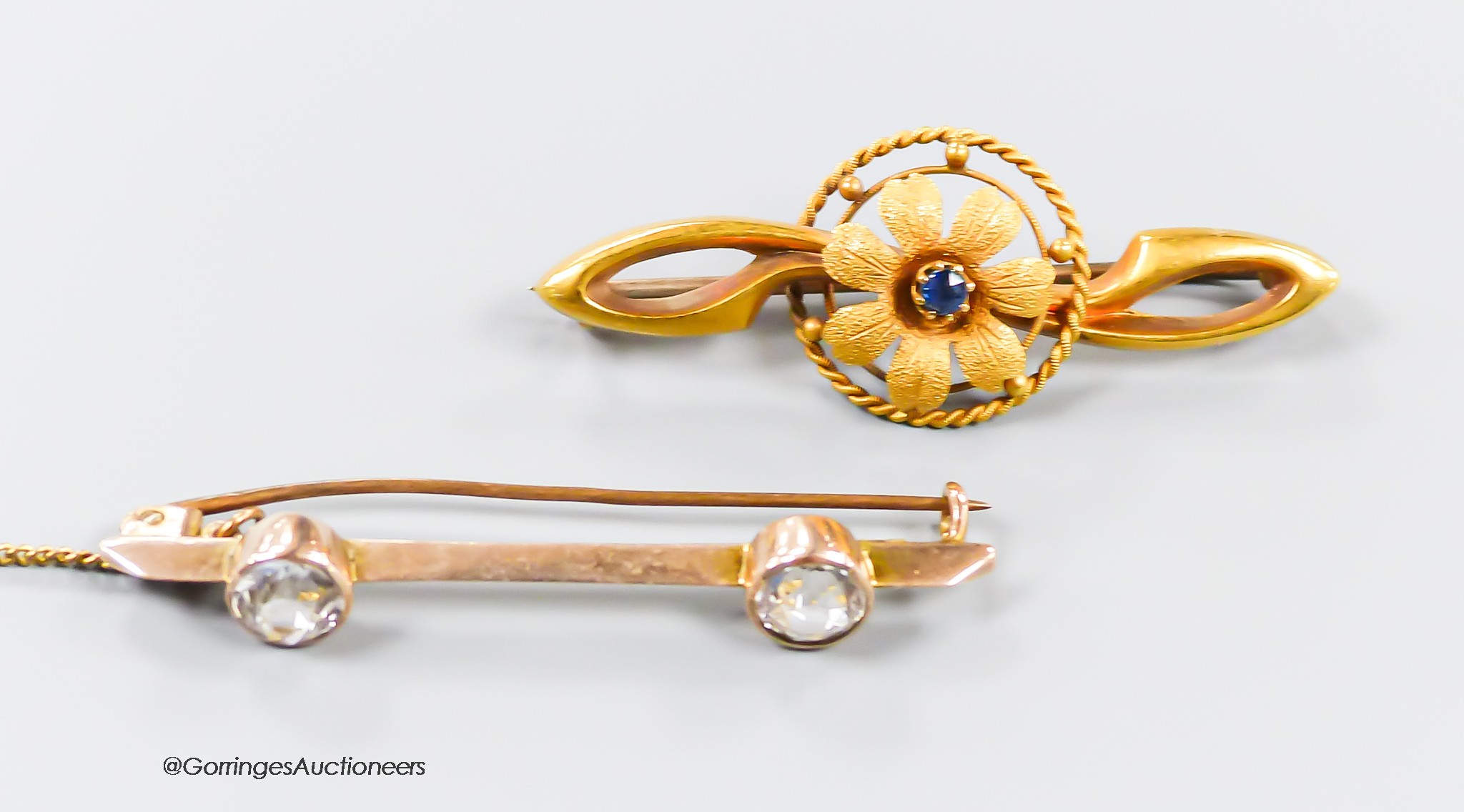 An Edwardian 15ct gold and sapphire set flower head bar brooch, 41mm, gross 2.6 grams and a 9ct and two stone paste set bar brooch, gross 2.6 grams.